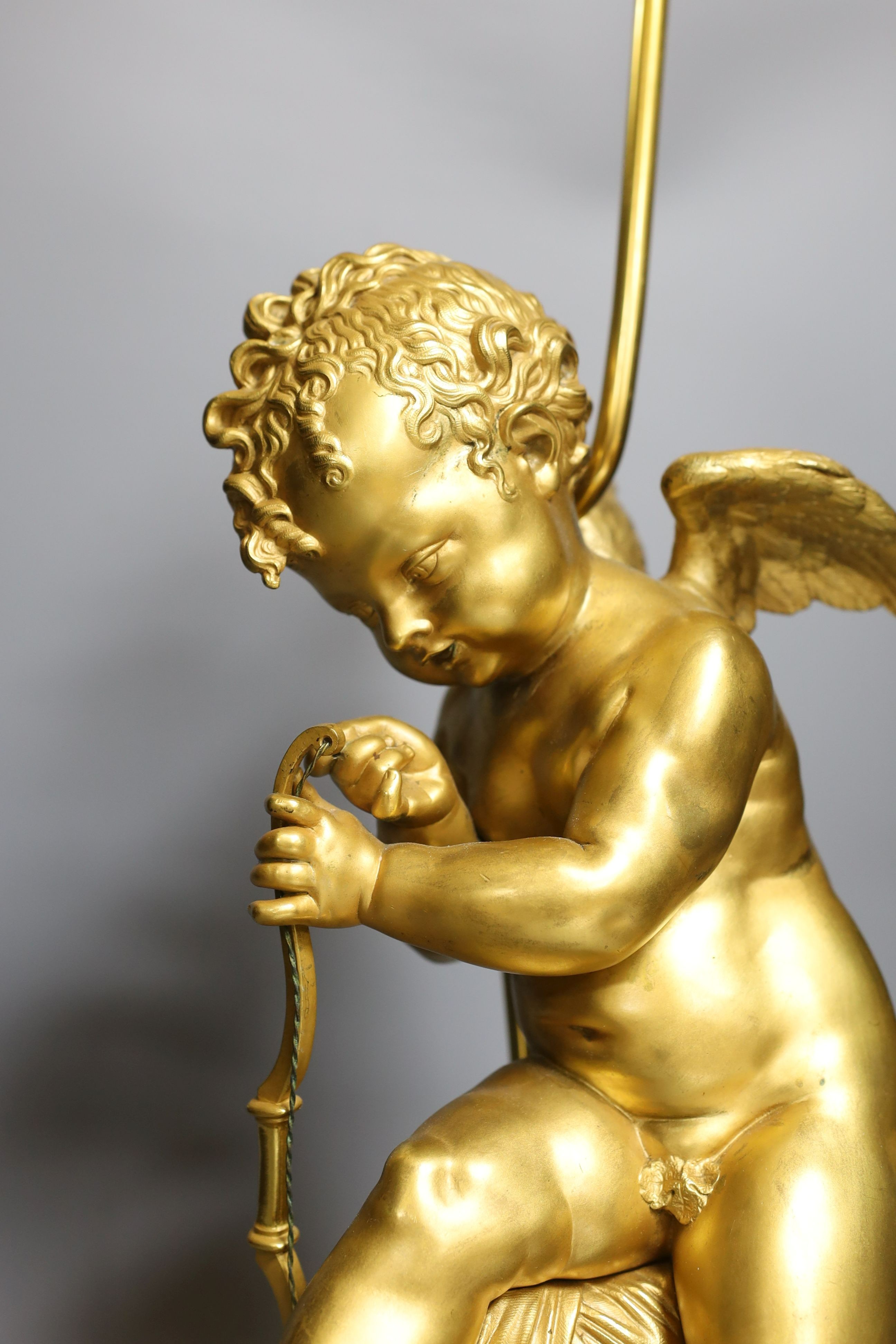 A gilt bronze seated Cupid figural lamp on mount - 58cm tall
